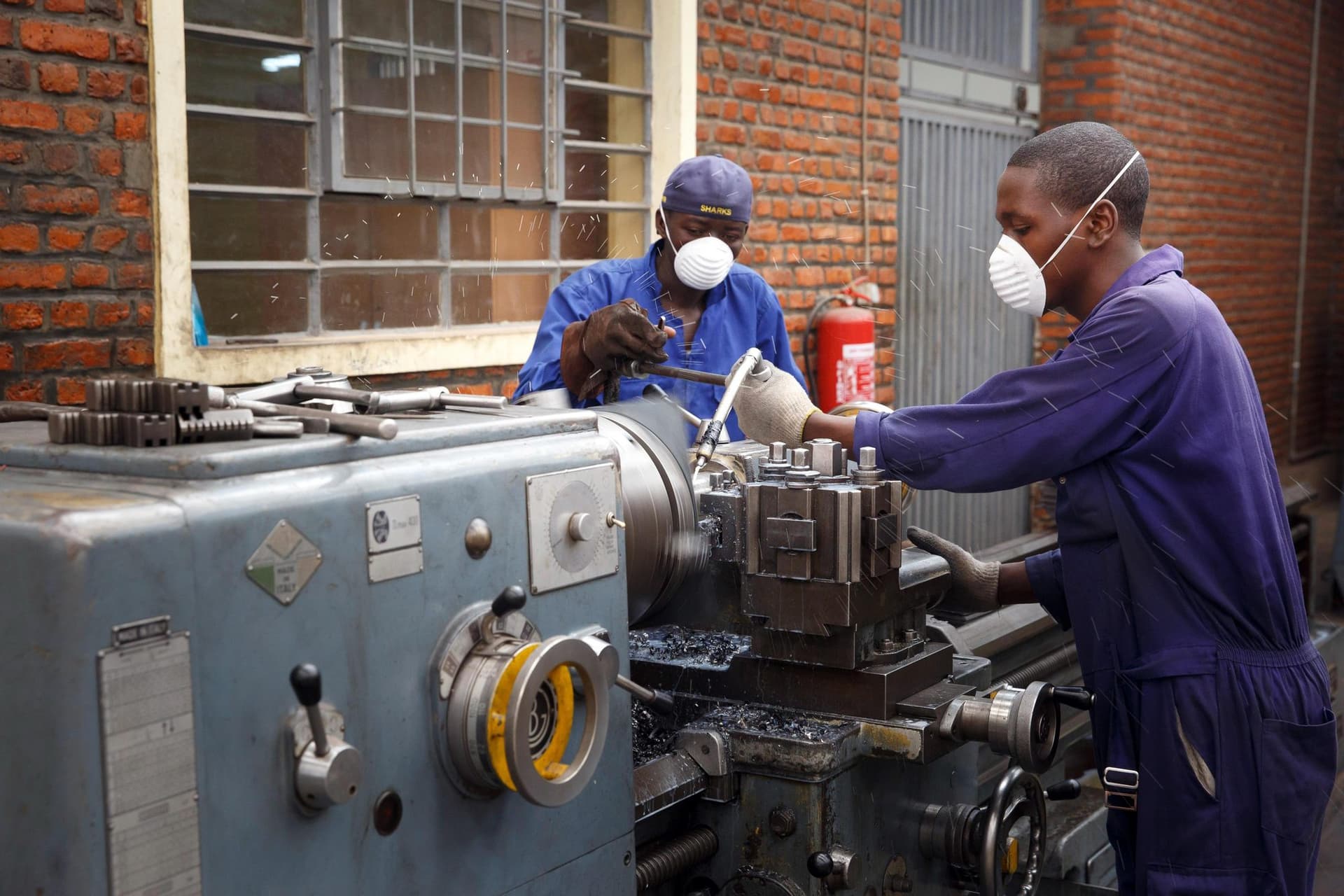 Technicians machining a metal part on a lathe