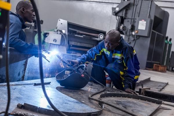 Technicians welding a steel plate in the workshop